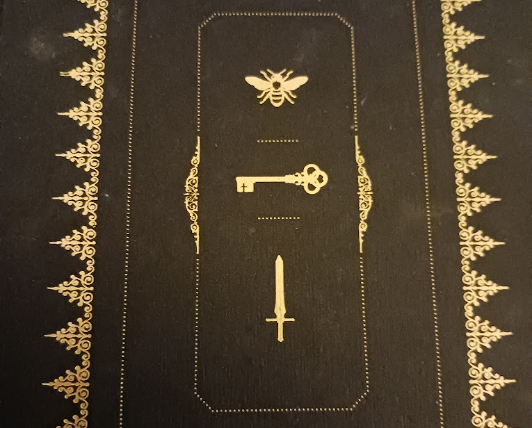 The bee, key, and sword motifs surrounded by a triangular border