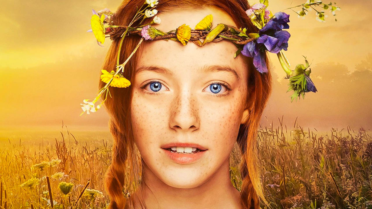 Anne's face is centered and takes up most of the frame. Her red hair is in two braids with one over each shoulder. She's wearing a flower crown and her eyes are a bright blue.