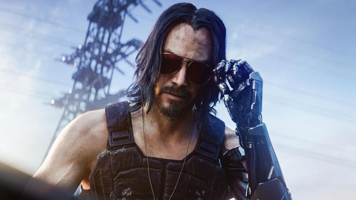 Keanu Reeves wearing sunglasses with a metal left arm. He is using his metal arm to take his sunglasses off. 