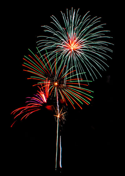 three explosions of fireworks in a black sky