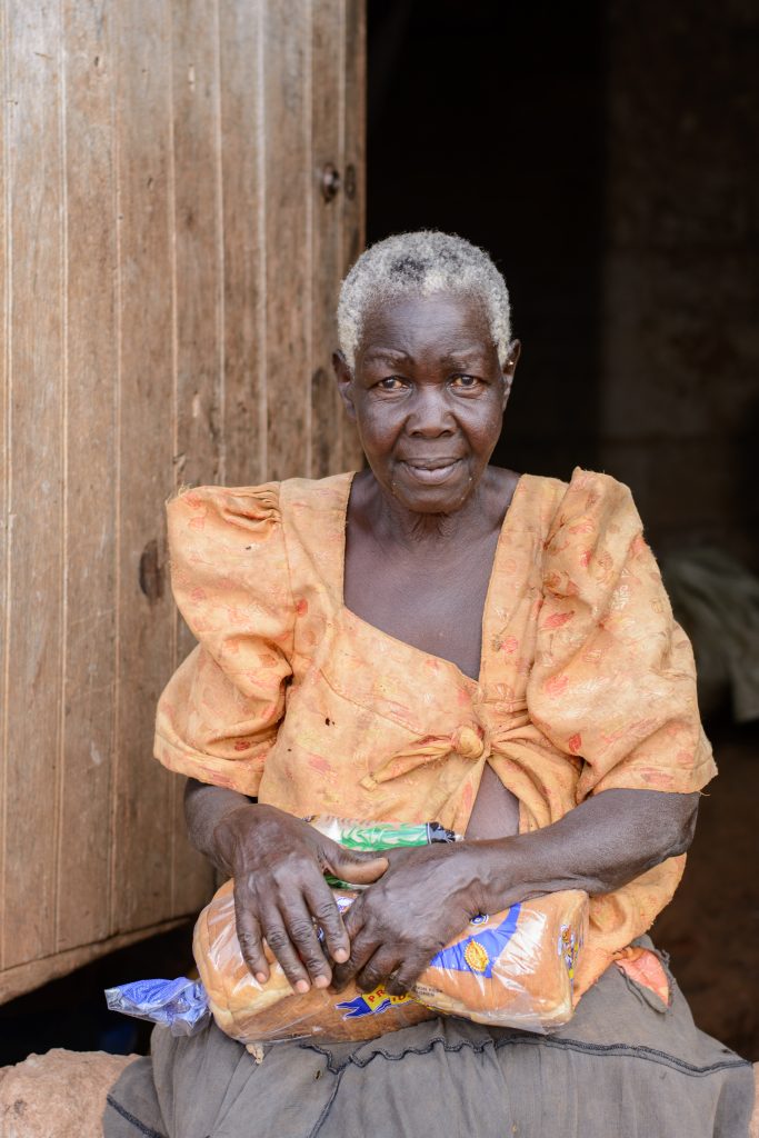 Photo of elderly African American woman sitting next to a door. She is looking directly at the camera.