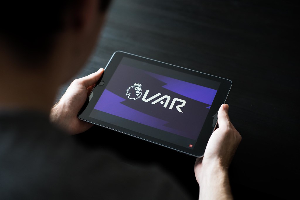 A person holding an ipad with the VAR logo on it