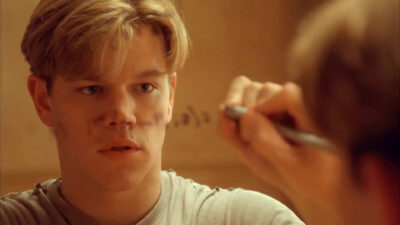 Will Hunting writing a math equation on a clear board.