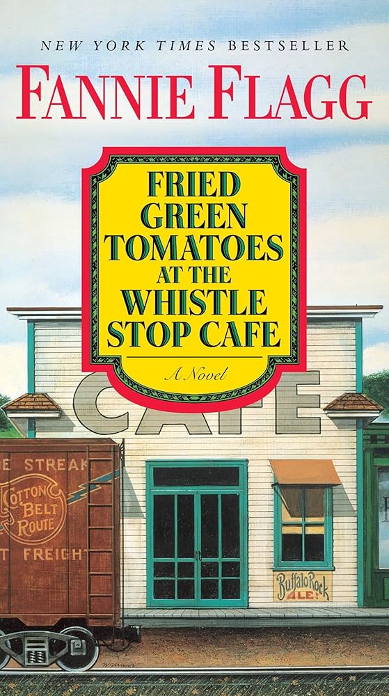 A book cover featuring an illustrated cafe building with train tracks in the foreground. A train is passing by on the tracks, and the visible words written on the train car are "STREAK," "Cotton Belt Route," and "Freight." Words written on the building are "CAFE" and "Buffalo Rock Ale." The top half of the image is a blue sky with the text "NEW YORK TIMES BESTSELLER" and the author's name, "Fannie Flagg". In the center of the cover is the text, "FRIED GREEN TOMATOES AT THE WHISTLE STOP CAFE" and "A Novel".