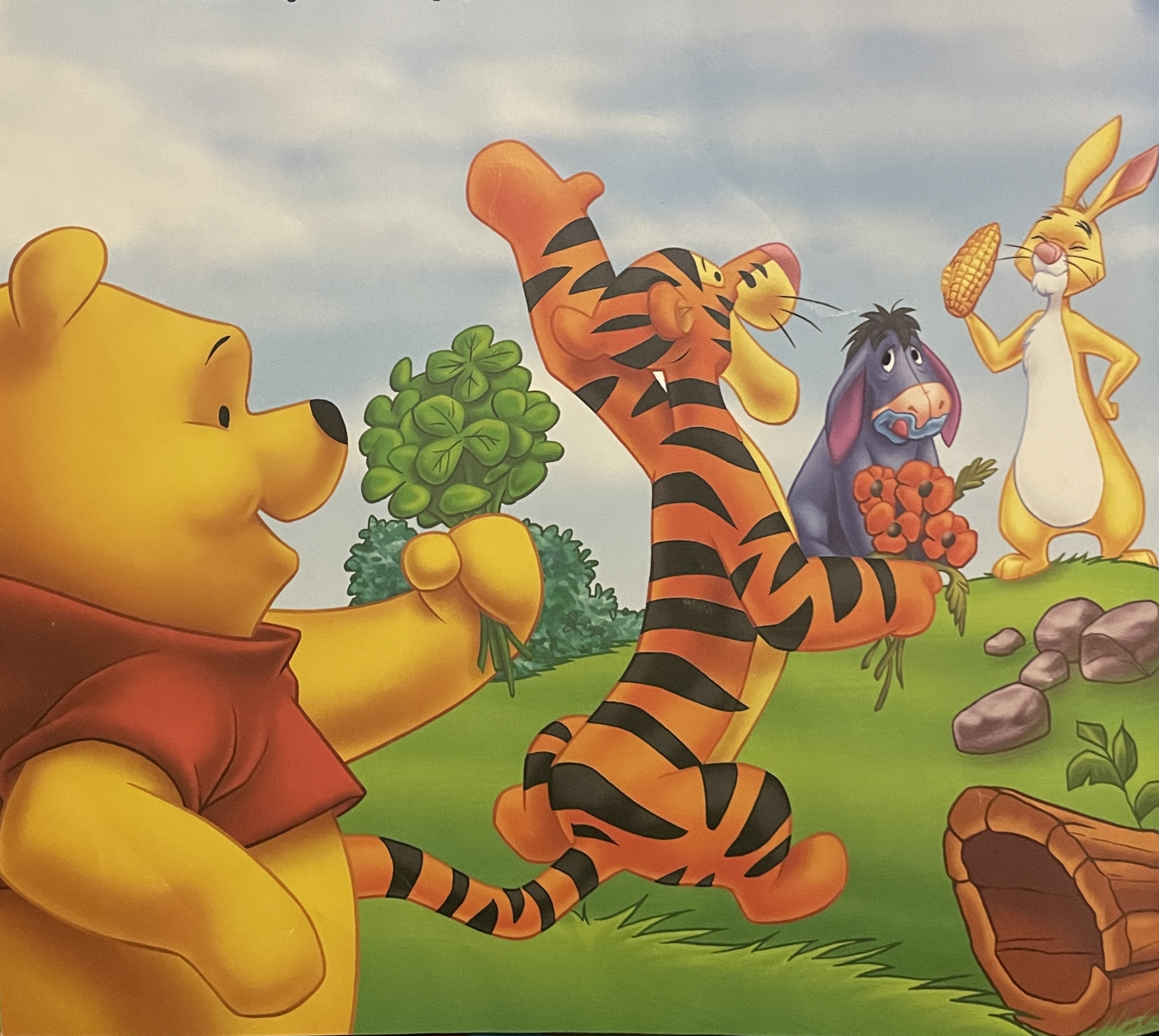 A colorful illustration of the Winnie the Pooh crew including Winnie the Pooh with four leaf clovers, Tigger with orange flowers, Eeyore with his tongue out, licking blueberry remnants off his face, and Rabbit with corn.  The crew is happily gathering.